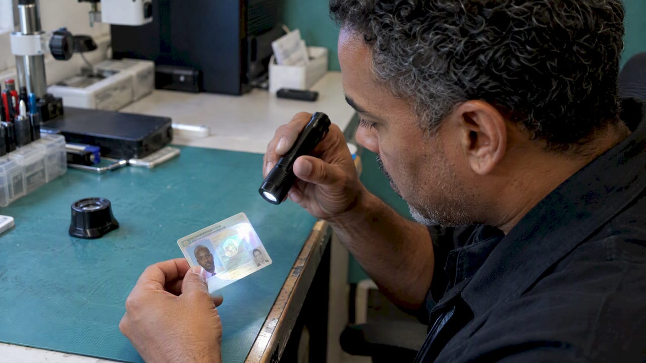 Examiner tilts a driver's license under light